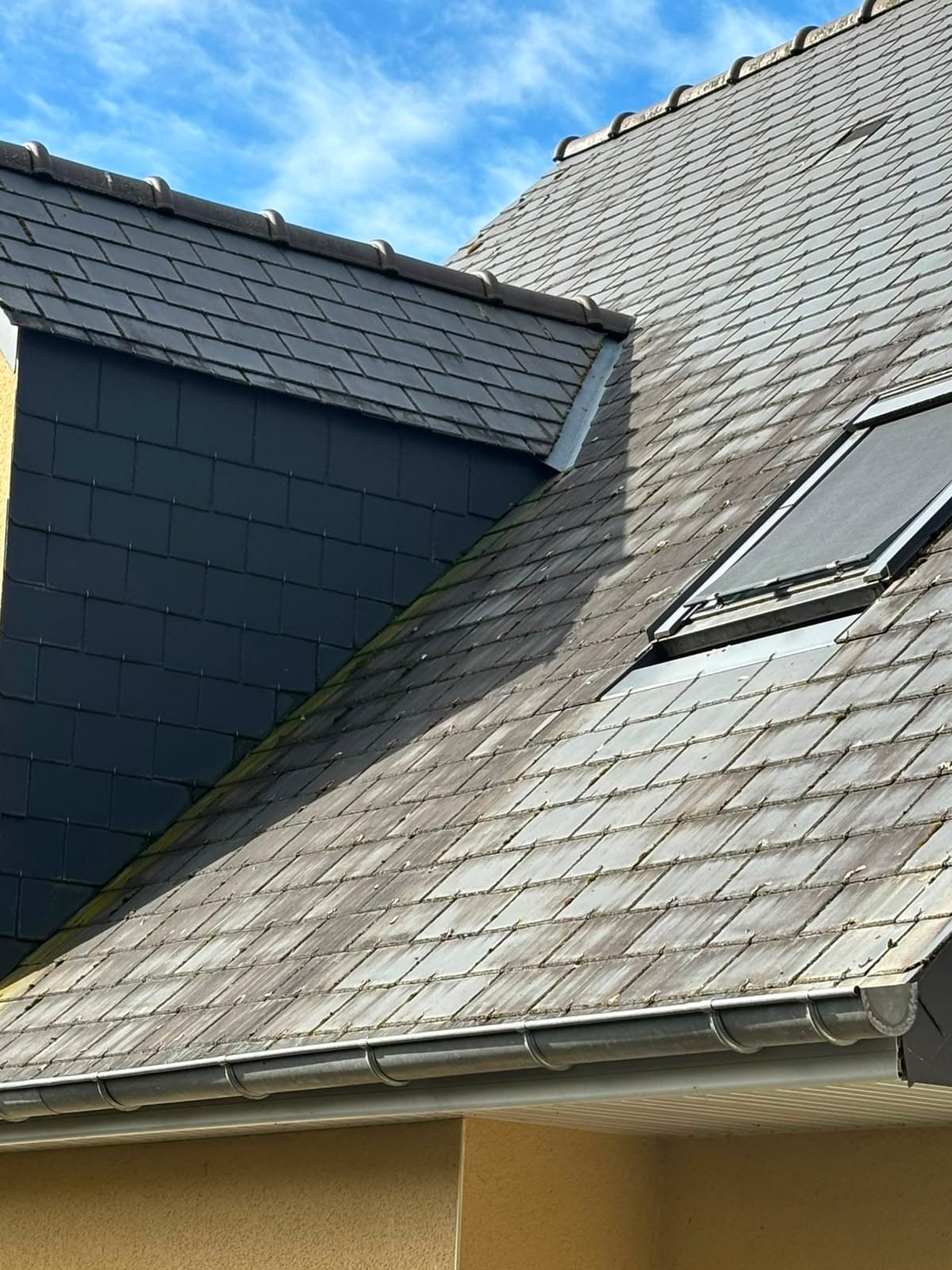 Noue de toiture au pied d'un chien-assis, zinc visible entre les deux versants